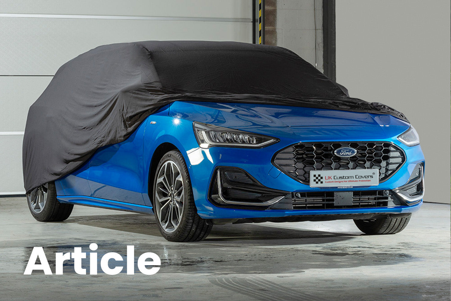 Blue Ford Focus with a black indoor car cover over the top showing the front of the car 