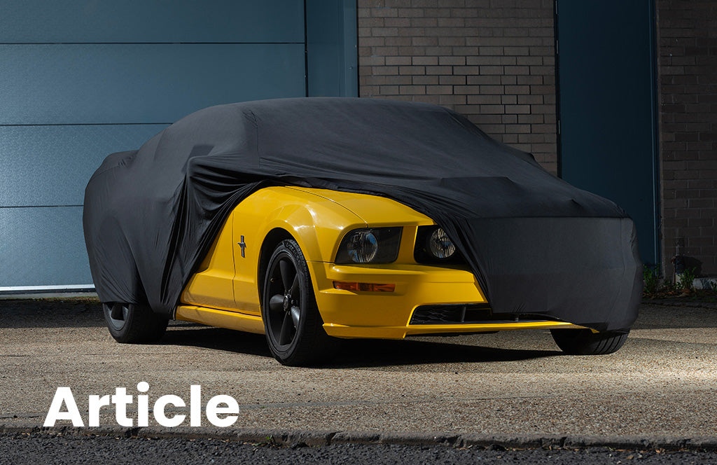 Yellow Ford Mustang with a black indoor car cover over the top showing the side of the car 